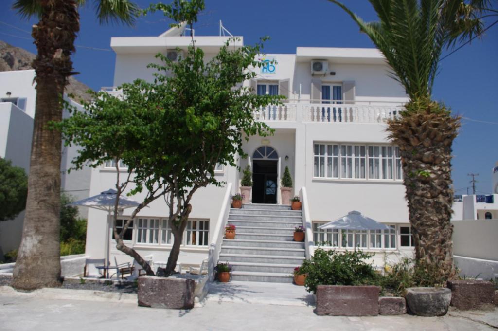 a white house with stairs and palm trees at Kamari Blue Boutique Hotel in Kamari