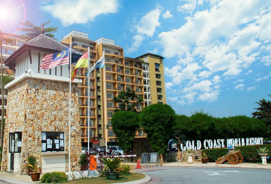 un edificio alto con banderas delante en Qastury Gold Coast Morib Resort en Morib