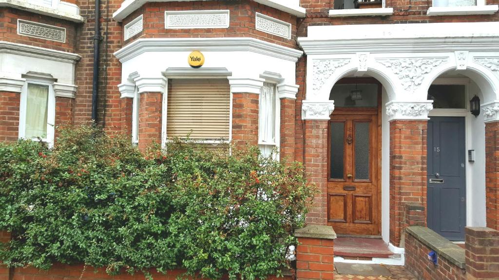 a brick house with a blue door and a bush at Victorian Superior Property in London