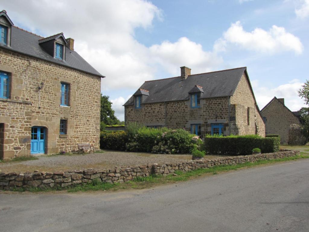 an old brick house with a stone wall next to a street at SARL Verrerie Royale in Val Couesnon