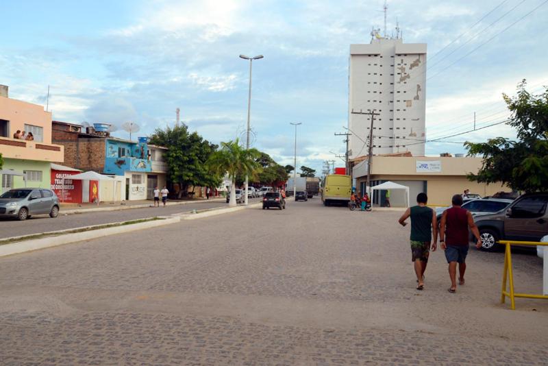 two men walking down a street in a town at Flat em Sao Jose da Coroa Grande in São José da Coroa Grande