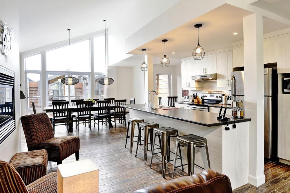 une cuisine et un salon avec un comptoir et des chaises dans l'établissement Chalet 15 Chemin des Quarante by Les Chalets Alpins, à Stoneham
