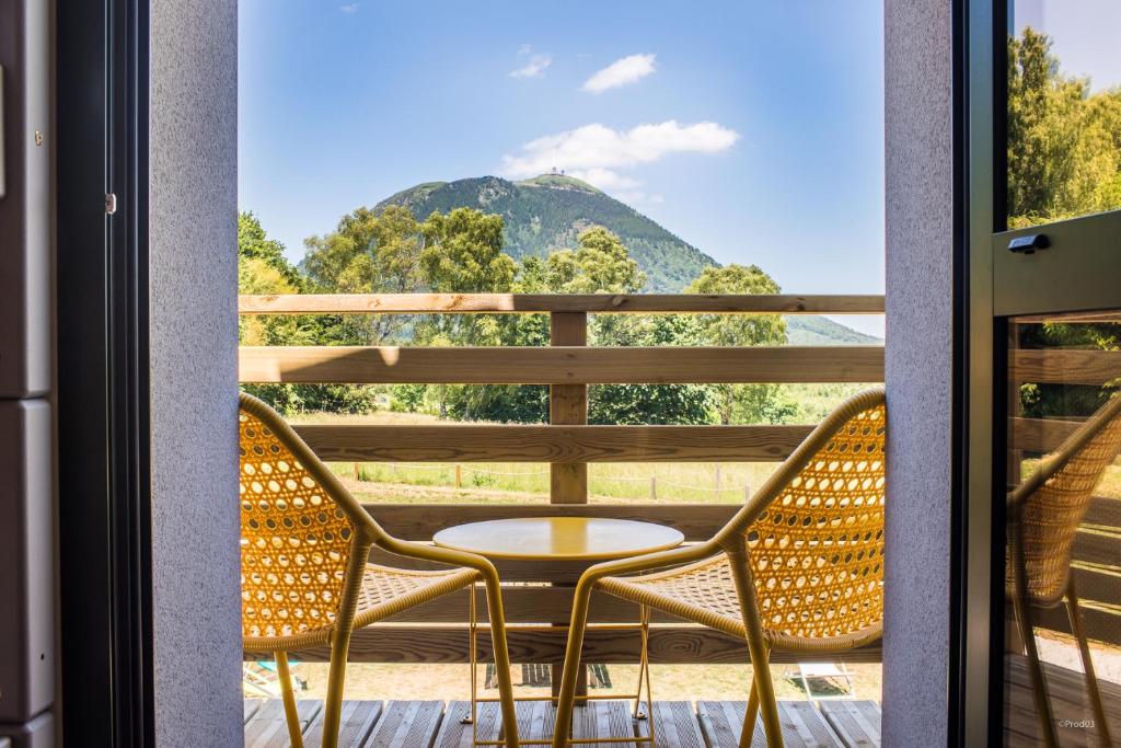 d'une table et de chaises sur un balcon avec vue sur la montagne. dans l'établissement Archipel Volcans, à Saint-Genès-Champanelle