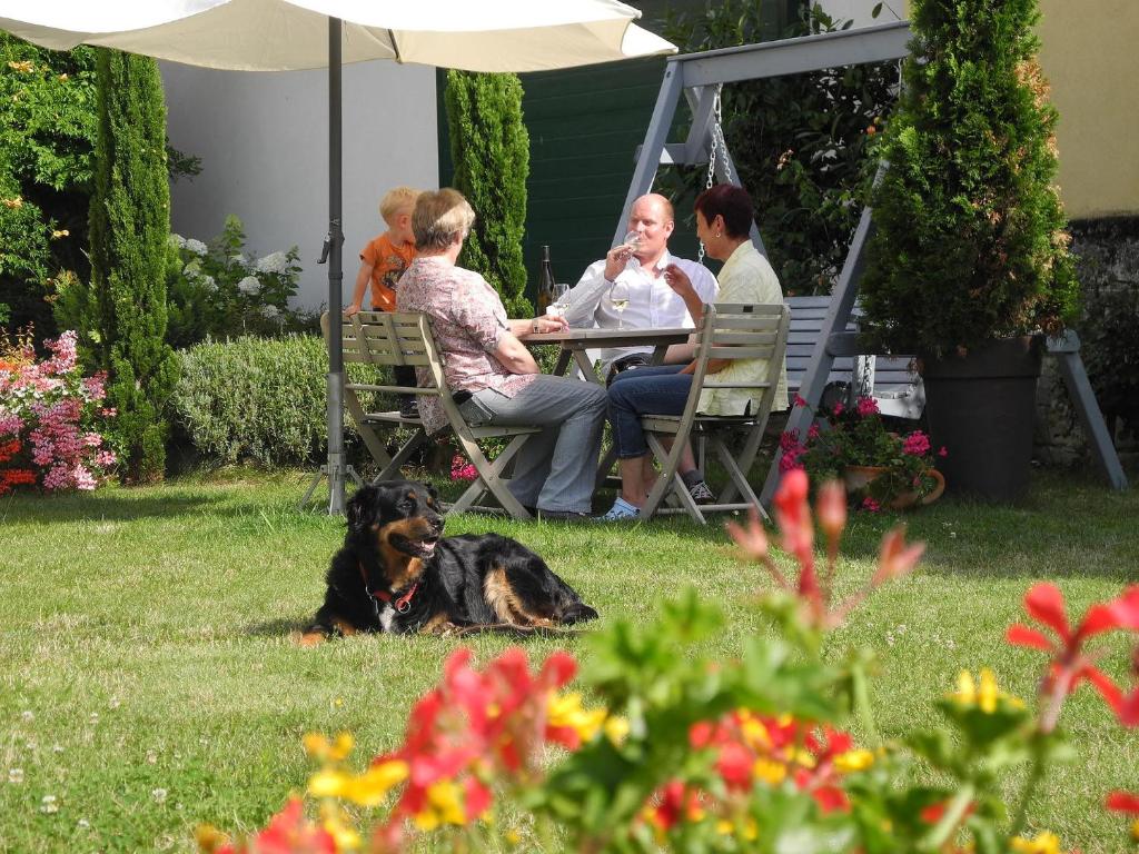 un grupo de personas sentadas en una mesa con un perro en Winzerhof Schwerdt, en Bad Dürkheim