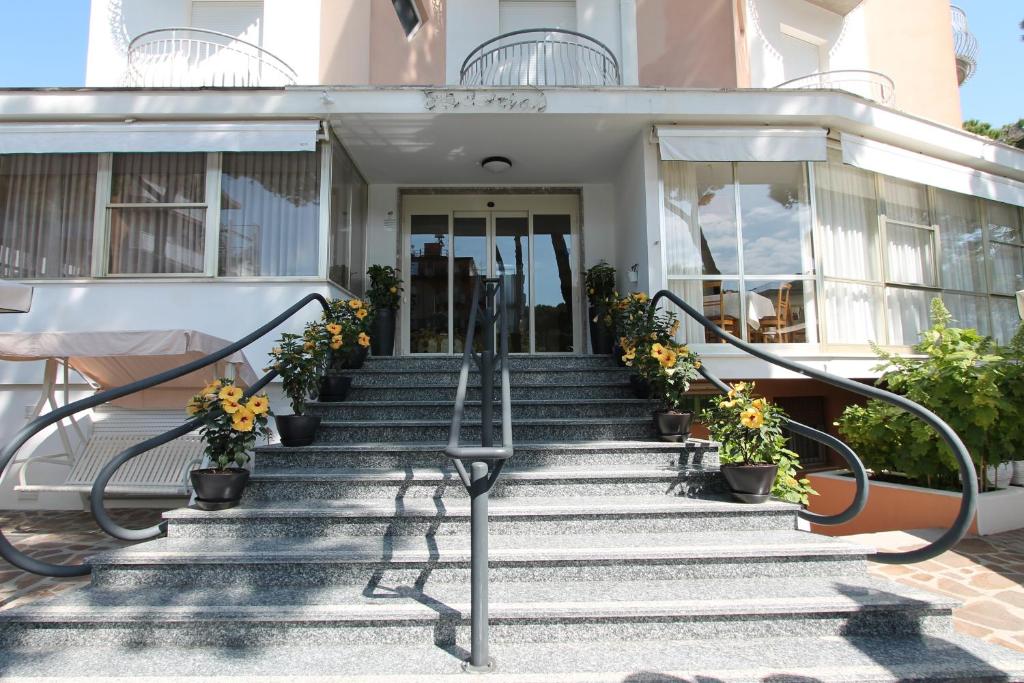 una casa con escaleras y flores delante en Hotel Escorial en Cervia