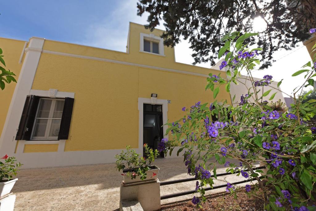 モンタルバーノにあるVilla Ricciardi-Suite famigliare 1-zona Ostuniの紫の花の黄色い家