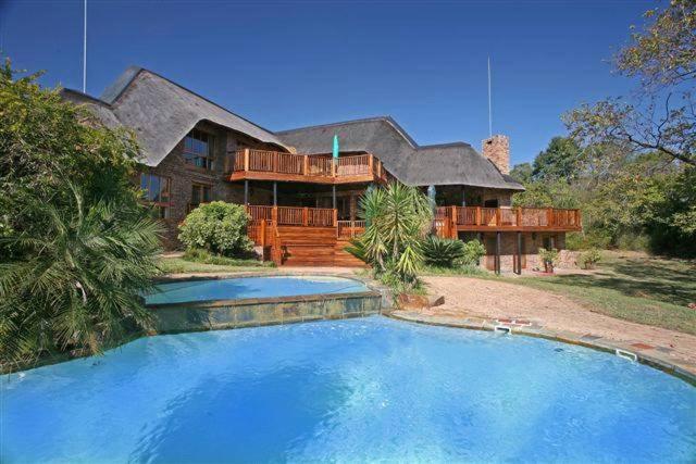 een groot huis met een groot zwembad ervoor bij Kruger Park Lodge 401 in Hazyview
