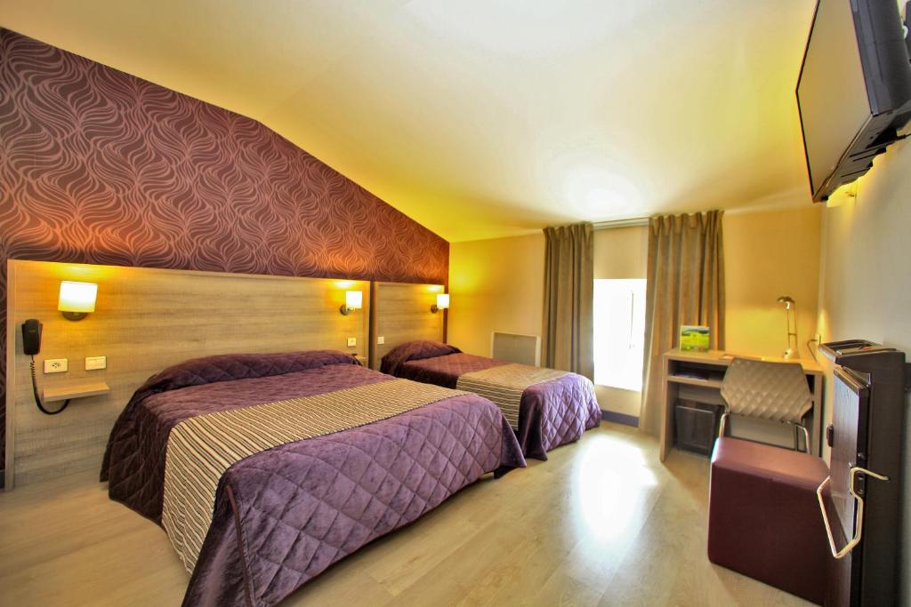 a hotel room with two beds and a flat screen tv at Logis Hôtel Le Saint Georges in Vivonne