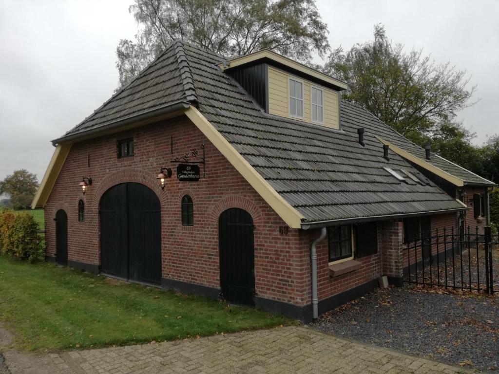 una casa de ladrillo rojo con techo de gambrel en Vakantiehuis Ganderhoeve, en Gaanderen