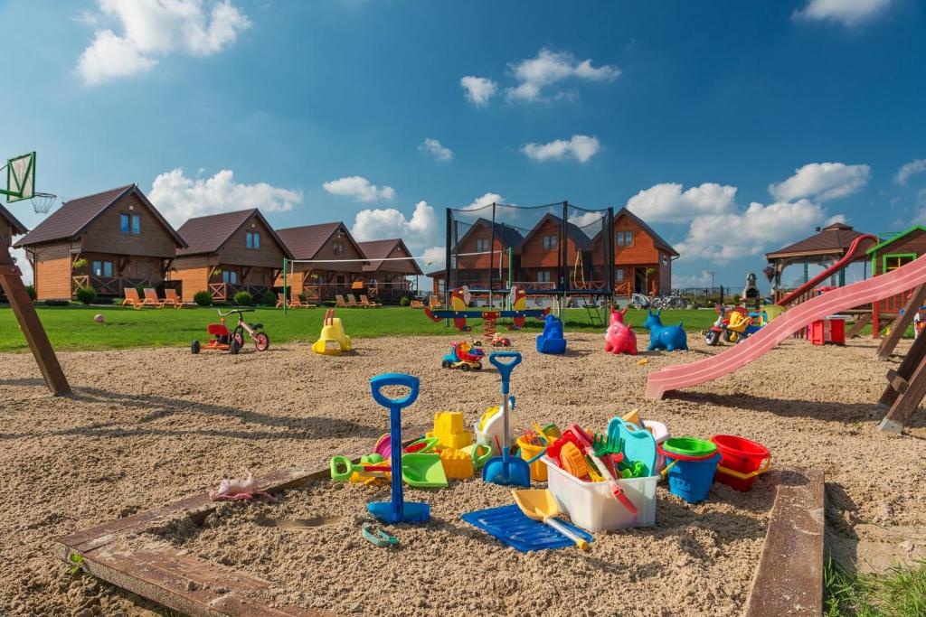 un parque infantil con juguetes en la arena y casas en Domki Magnati en Władysławowo