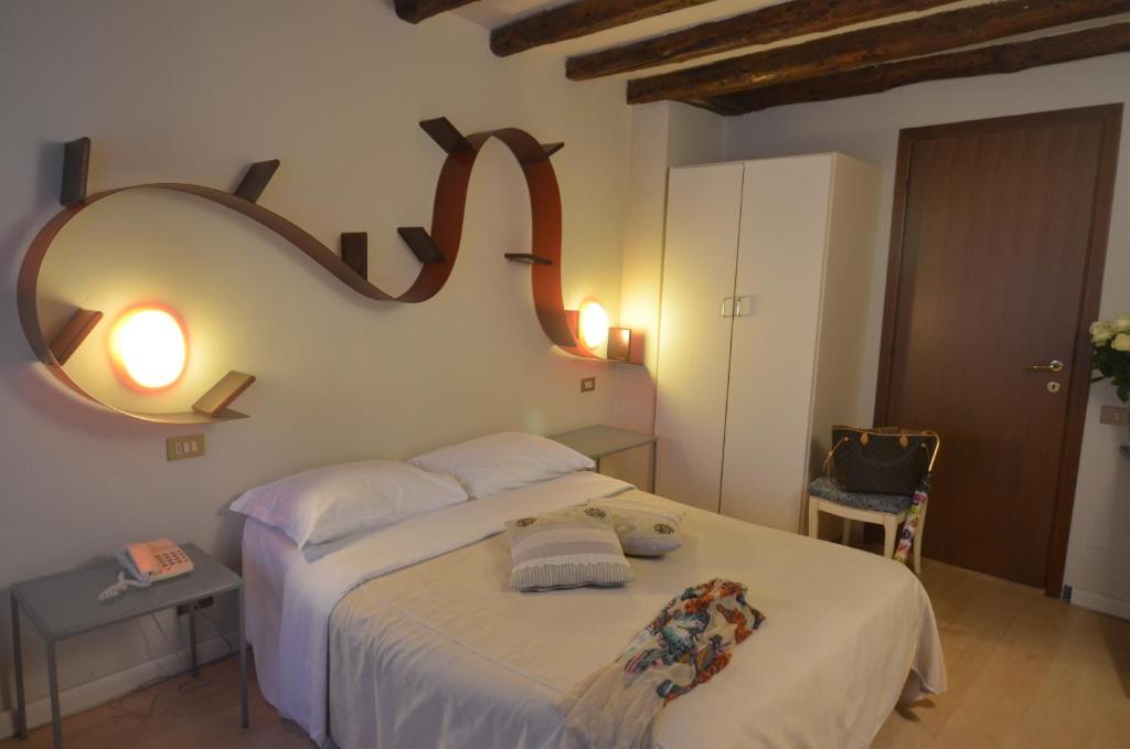 a bedroom with a large white bed with a mirror at Piccolo Tiepolo in Venice
