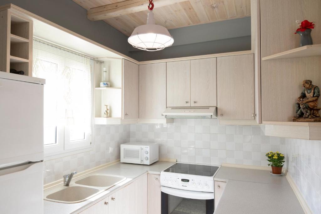 a kitchen with white cabinets and a sink and a microwave at Virginia Seaside Villas in Agía Paraskeví