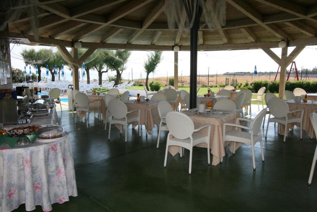 a dining room with tables and white chairs and trees at Residence Club Barbara in Ostuni