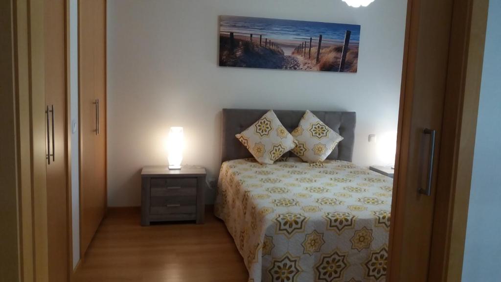 1 dormitorio con cama y mesita de noche con lámpara en Apartamento Novo com Piscina Olhão, en Olhão