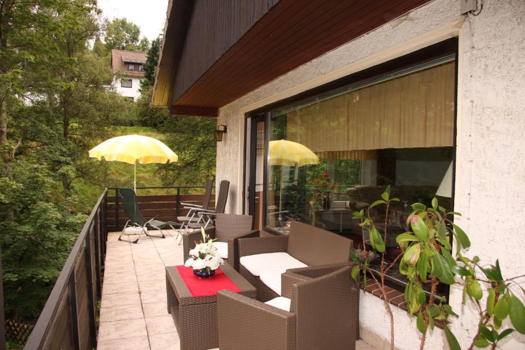 a balcony with chairs and a table and an umbrella at Kurpark Domizil in Altenau