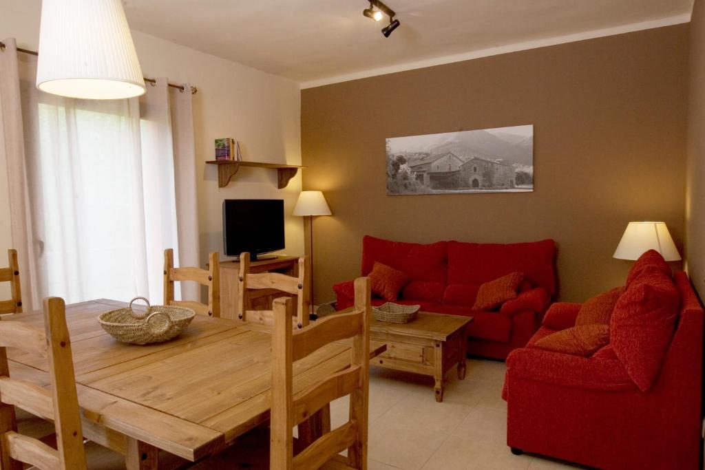 古奧巴蒂達特的住宿－Cal Metge de Gualba，客厅配有桌子和红色沙发