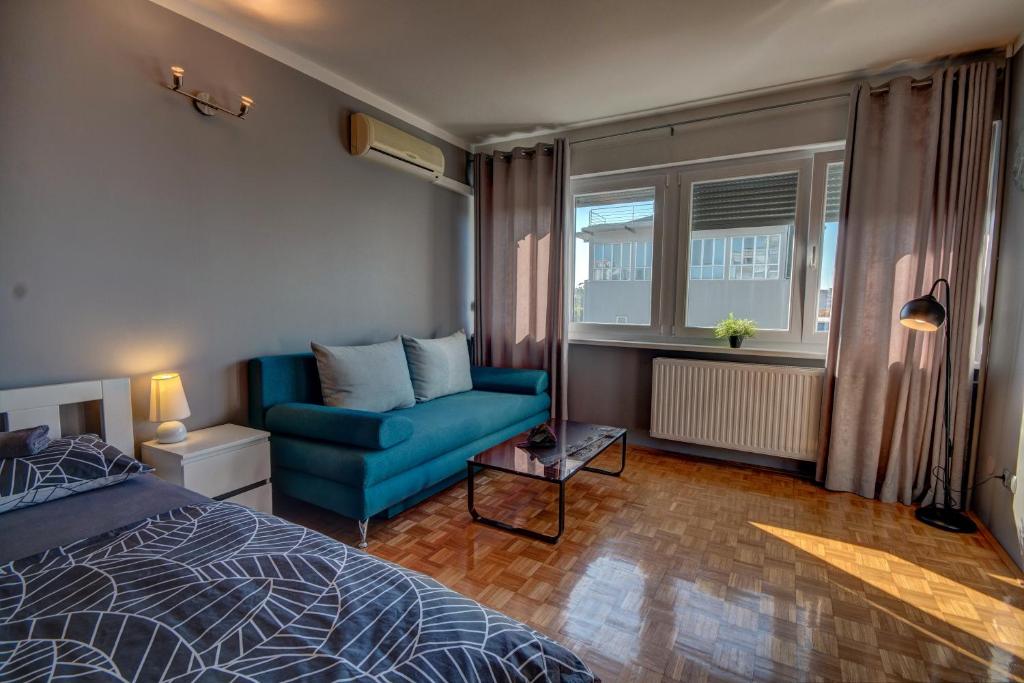 een slaapkamer met een blauw bed en een blauwe stoel bij Apartment Barnjak - Novi Zagreb in Zagreb