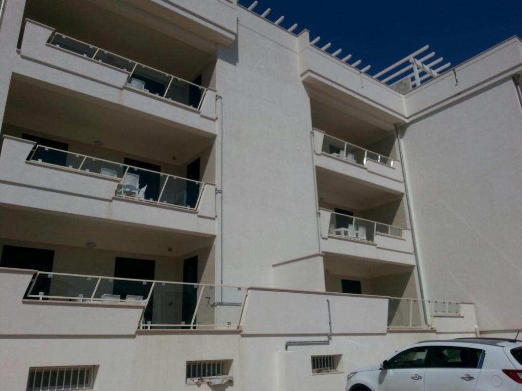 ヴィエステにあるLa Rotonda Sul Mareのバルコニー付きの白い建物、正面に駐車した駐車場
