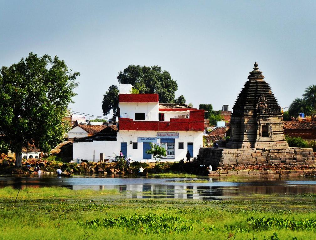 a building and a temple next to a body of water at Friends in Khajuraho in Khajurāho