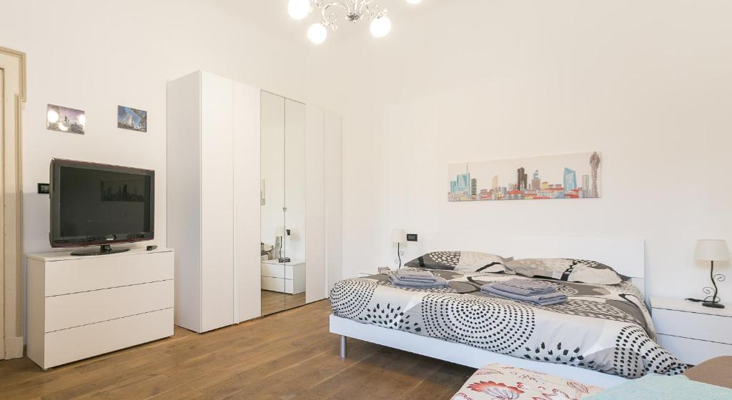 a white bedroom with a bed and a flat screen tv at Borsieri 29 - Heart Of Isola in Milan