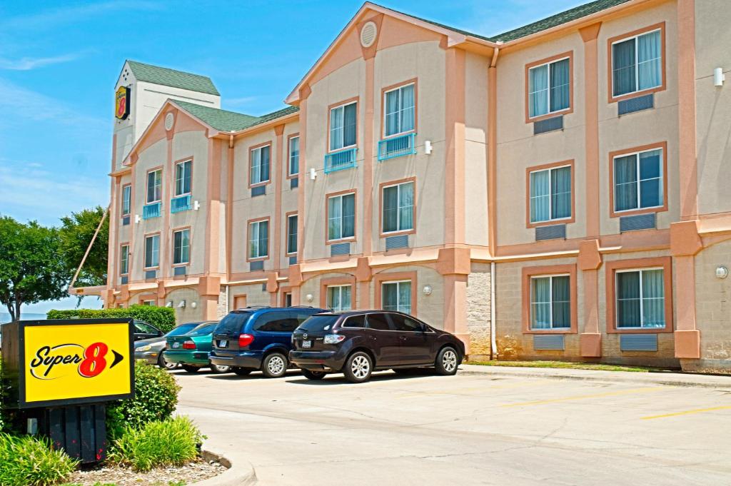 ein Gebäude mit Autos auf einem Parkplatz in der Unterkunft Super 8 by Wyndham Irving/DFW Apt/North in Irving