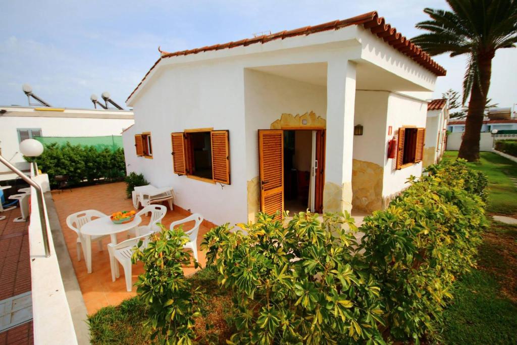 ein kleines weißes Haus mit einem Tisch und Stühlen in der Unterkunft Precioso Bungalow 11 in Playa del Ingles