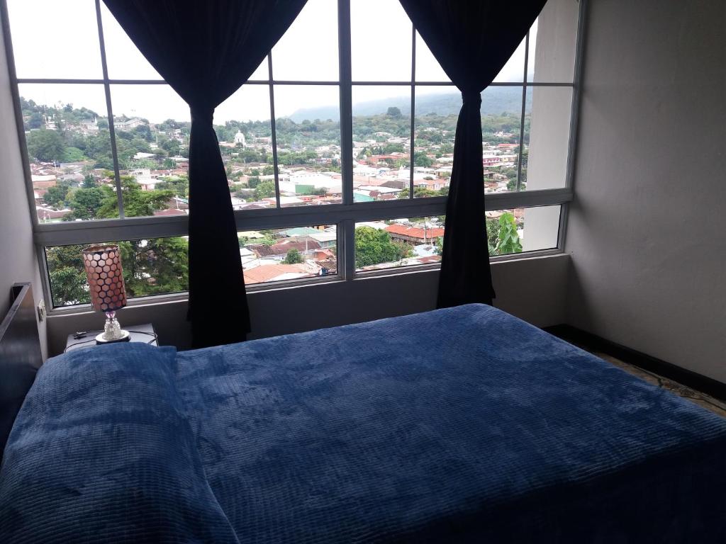 a bedroom with a blue bed in front of a window at El Balcón de Ataco in Concepción de Ataco