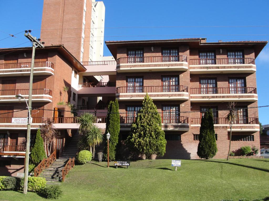 un gran edificio de ladrillo con un césped en frente en el Aparte Familiar Antu Alen I en Villa Gesell