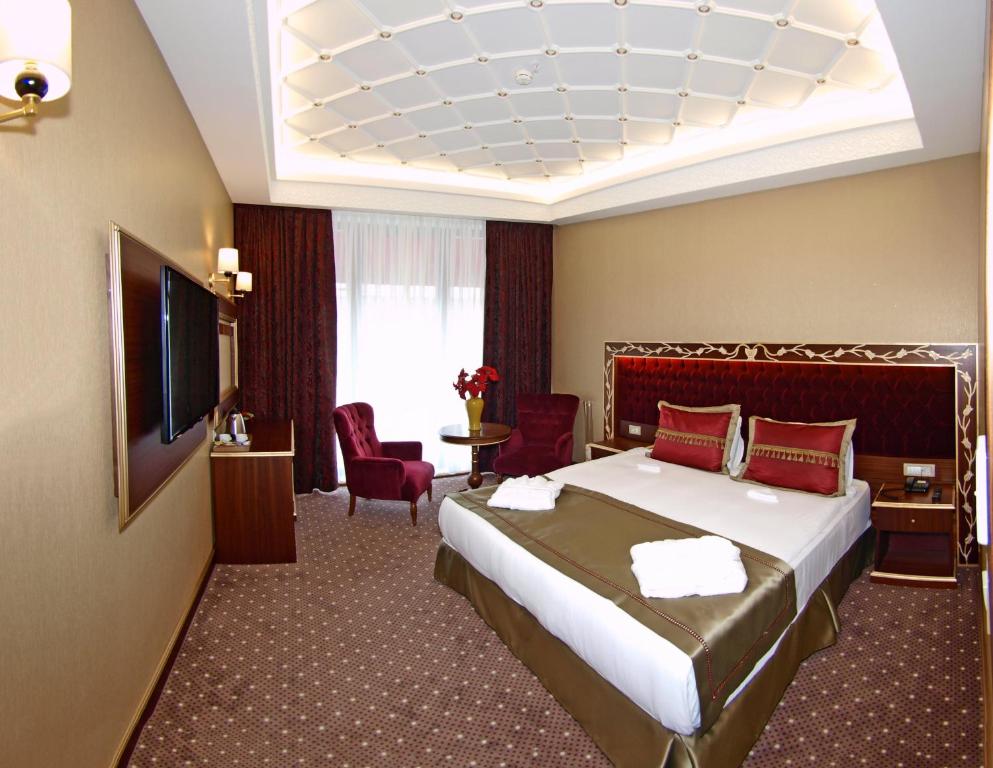 イスタンブールにあるMB Deluxe Hotelのベッド1台、薄型テレビが備わるホテルルームです。
