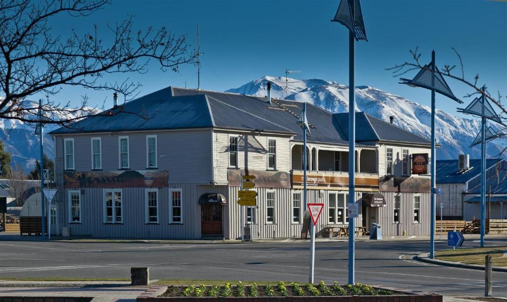 a large white building with a mountain in the background at The Brown Pub in Methven