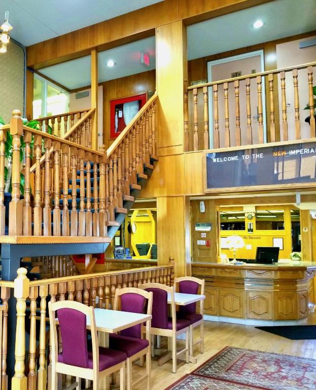 a restaurant with stairs and tables and purple chairs at New Imperial Inn in Cold Lake