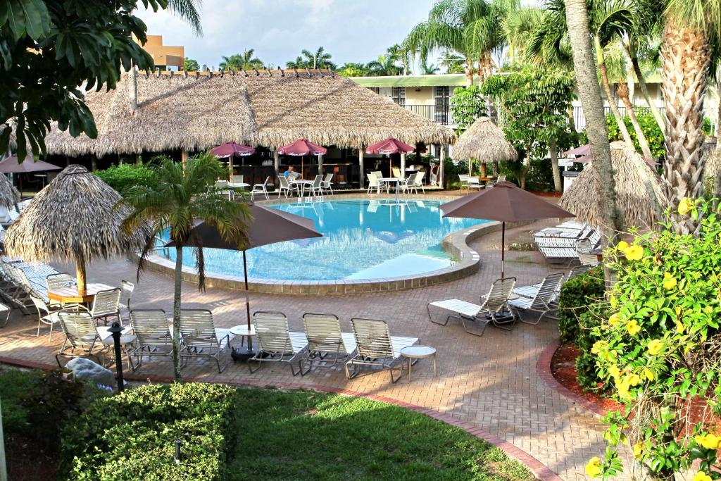 
a beach with a pool, chairs, tables and umbrellas at Gulfcoast Inn Naples in Naples

