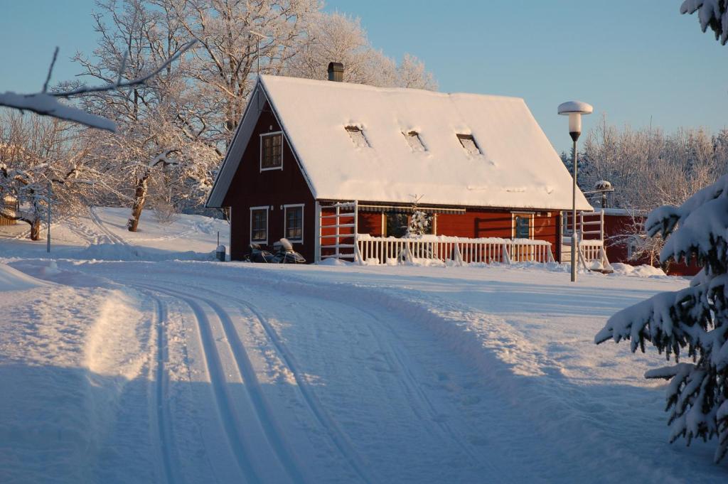 a red barn with a snow covered roof on a snowy road at Madsa Recreational Center in Otepää