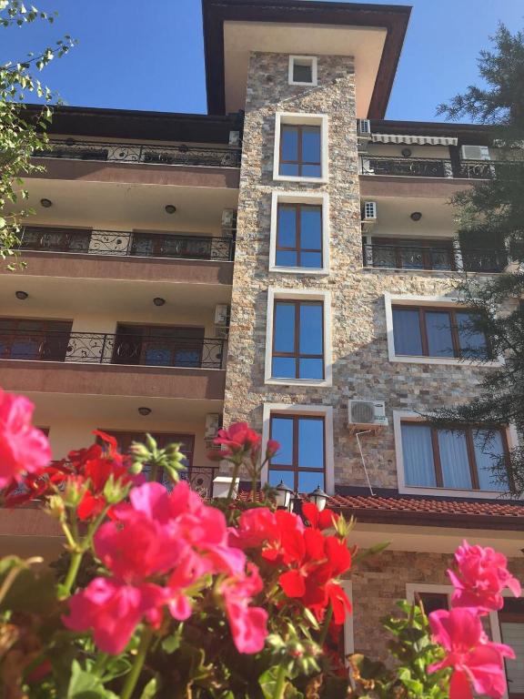 a tall building with red flowers in front of it at Rich-3 SP apartments in Ravda