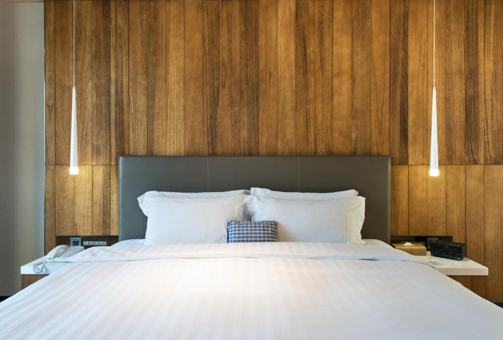 a bedroom with a large white bed with wooden walls at Home Hotel in Taipei
