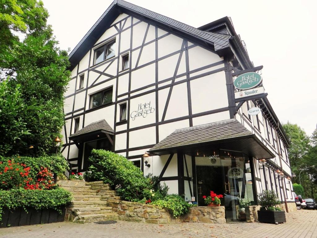 a white and black building with flowers in front of it at Hotel Gastgeb in Essen