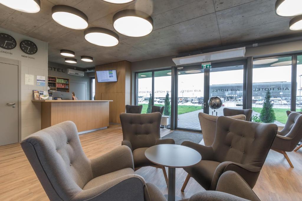 a waiting room with chairs and tables and windows at Air Hotel in Karmėlava