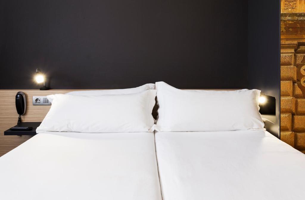 two beds with white pillows sitting next to each other at B&B HOTEL Granada in Pulianas