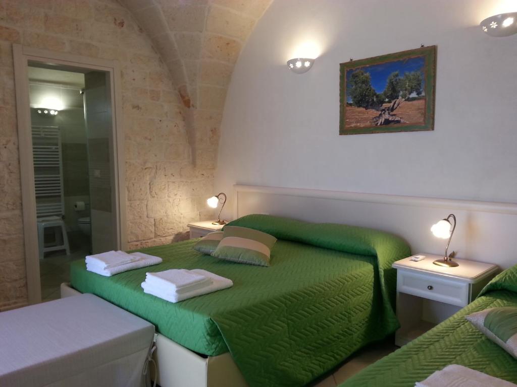 1 dormitorio con cama verde y espejo en B&B Demetra, en Carovigno