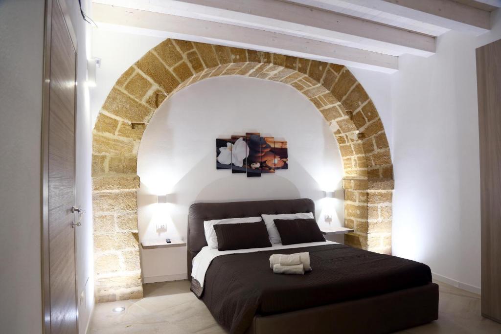 シラクーサにあるAppartamenti Maniaceのレンガの壁に大きなベッドが備わるベッドルーム1室が備わります。