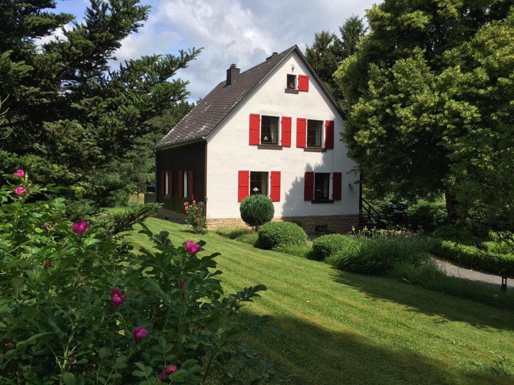 a white house with red shutters on a yard at Landhaus Camillas Höhe in Mirbach