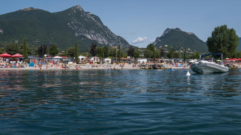 a boat in the water next to a beach at Villaggio Turistico Maderno in Toscolano Maderno