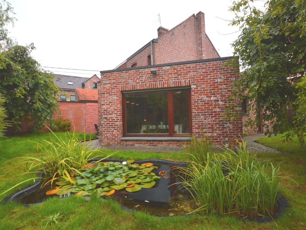 un jardin avec un étang et des nénuphars devant un bâtiment en briques dans l'établissement Family home with pond and terrace, à Le Bizet