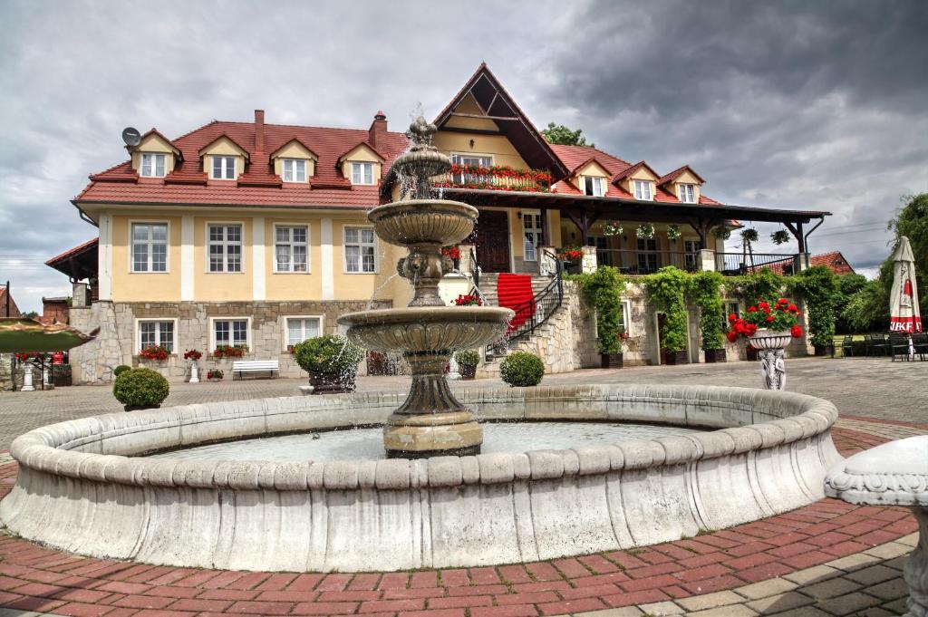 ein großer Brunnen vor einem großen Haus in der Unterkunft Zespół Pałacowo-Parkowy Bądzów in Polkowice