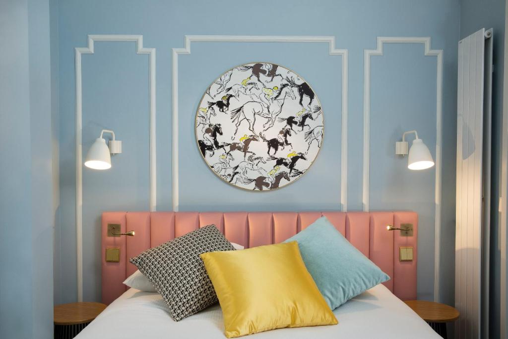 パリにあるオテル パステル パリのピンクのヘッドボードと壁に皿が付いたベッドルーム1室
