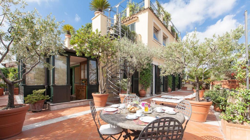 un patio al aire libre con mesa, sillas y árboles en Rental in Rome - Fontana Di Trevi Penthouse en Roma