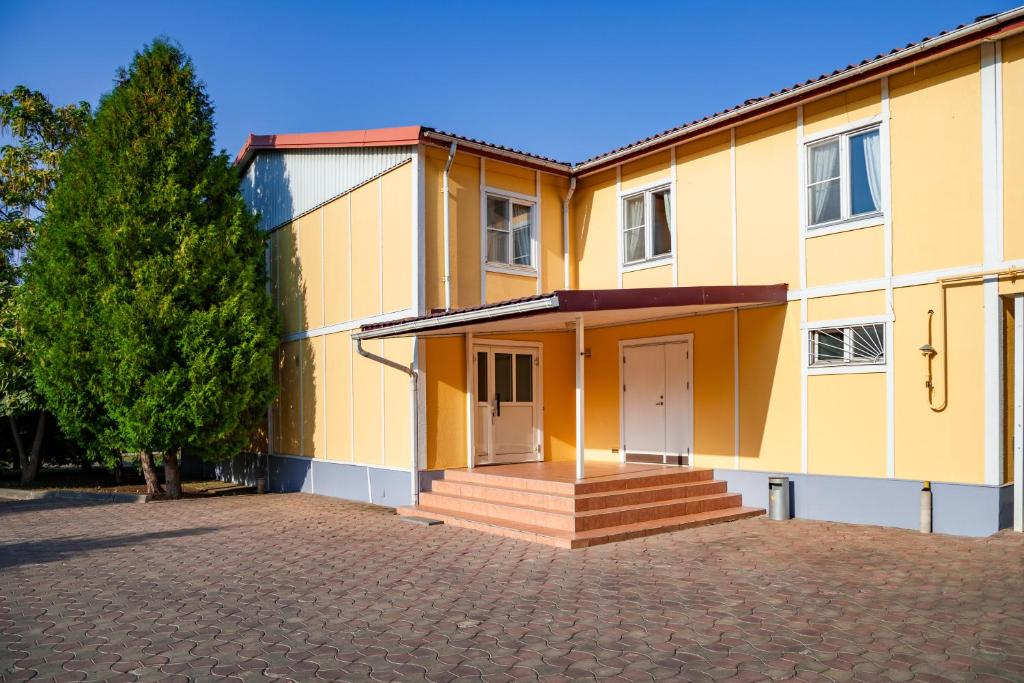 un grand bâtiment jaune avec une allée devant dans l'établissement Swedish Village Hotel, à Timachiovsk