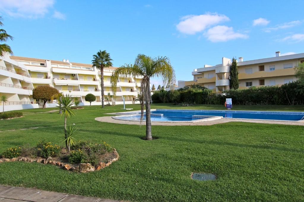 a resort yard with a swimming pool and palm trees at Falésia Marina - Clever Details in Vilamoura