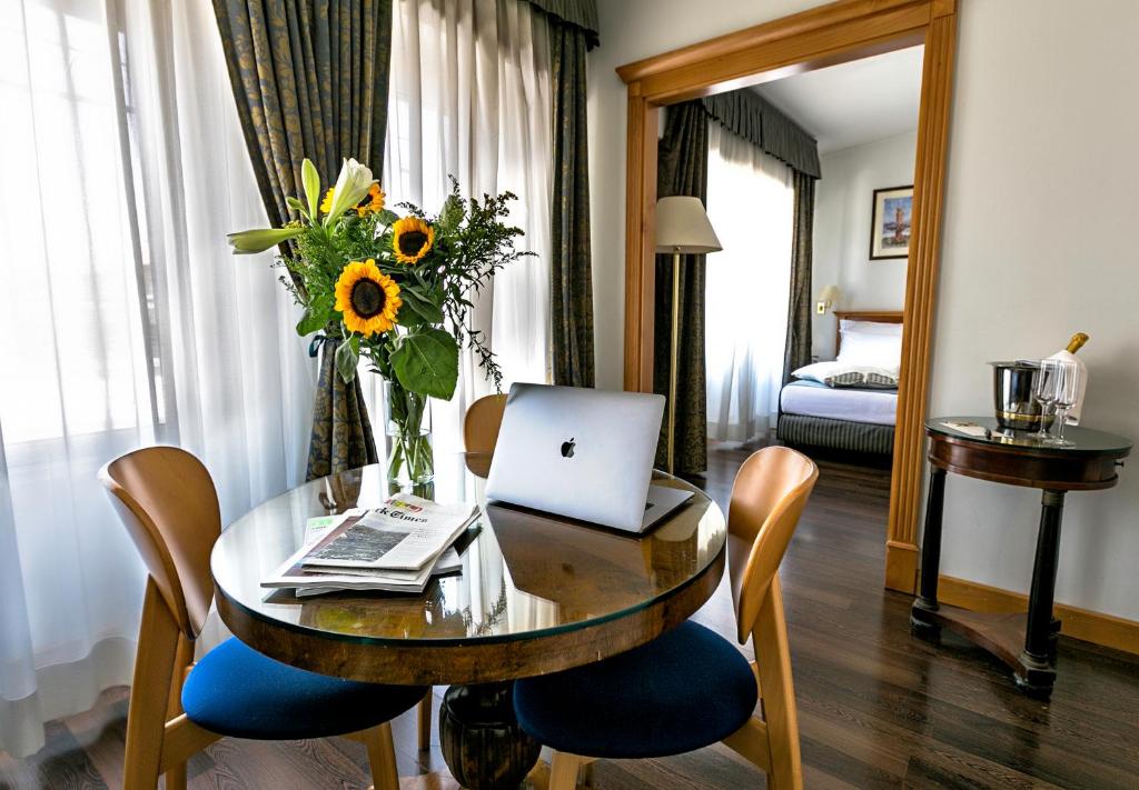 Habitación con mesa, ordenador portátil y flores en Hotel Diplomatic en Roma