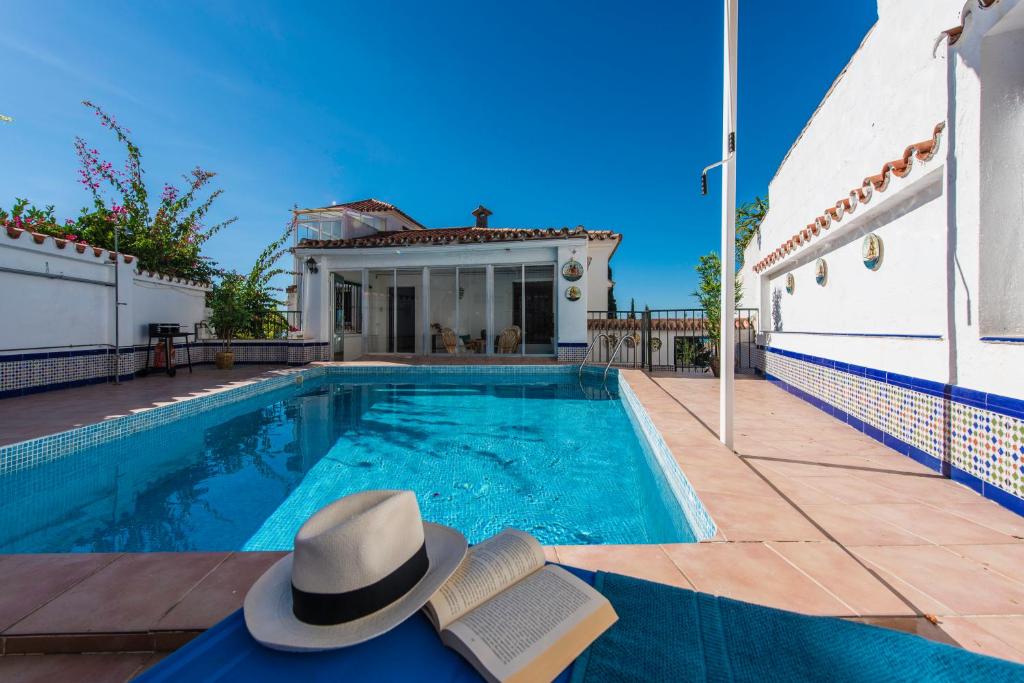 a hat and a book sitting next to a swimming pool at Atalaya Alta in Benalmádena